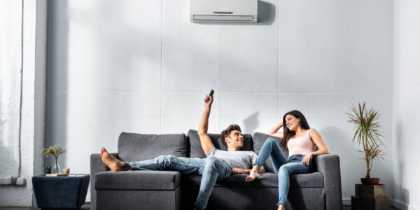handsome boyfriend switching on air conditioner and looking at smiling girlfriend Urgent air conditioning service, Delivering an urgent air conditioning service to beat the summer heat, Air Extreme Air Conditioning
